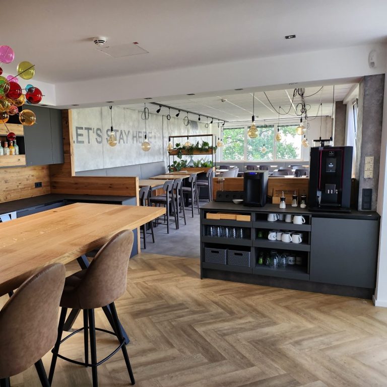 Moderne Innenansicht eines Cafés mit Holztheke und Sitzbereichen.